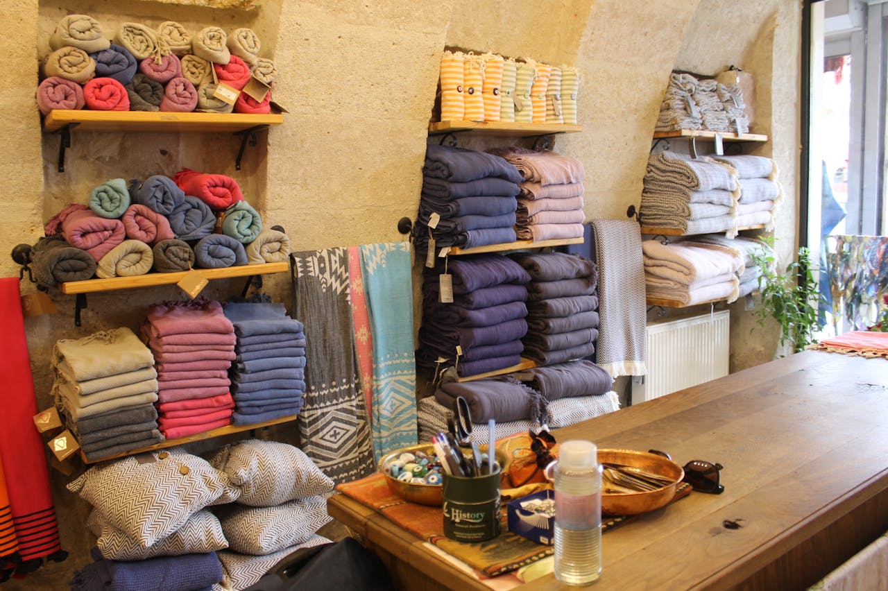 about-us-01 A warm, inviting shop in Göreme with neatly stacked colorful fabrics and textiles ready for sale.