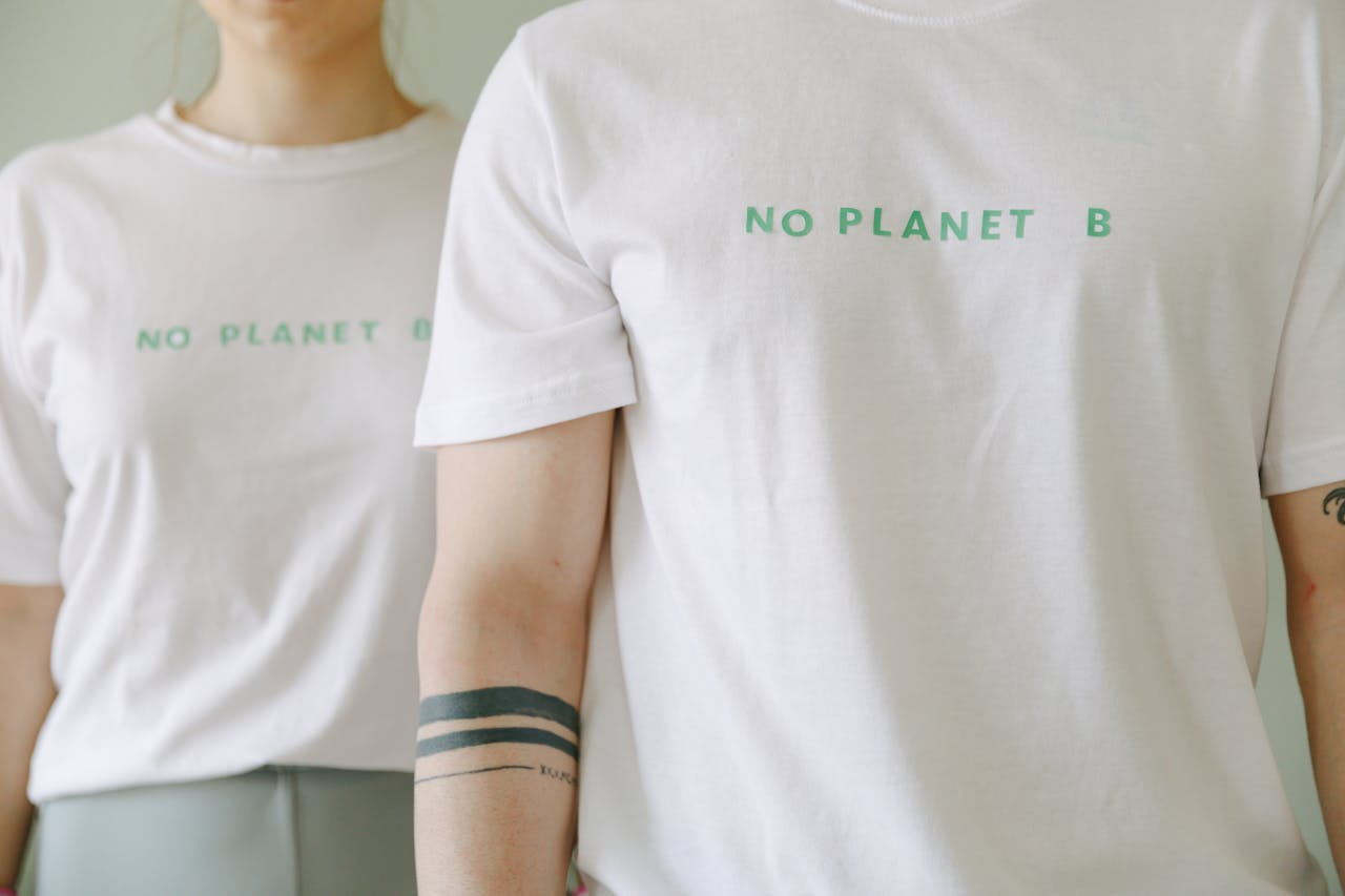 heros-img Close-up of two people wearing white 'No Planet B' T-shirts, promoting environmental awareness.